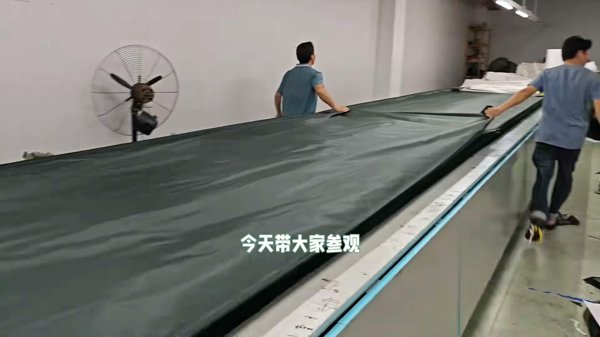 Workers handling tent fabric on a production table in Seawing's Facebook Reel