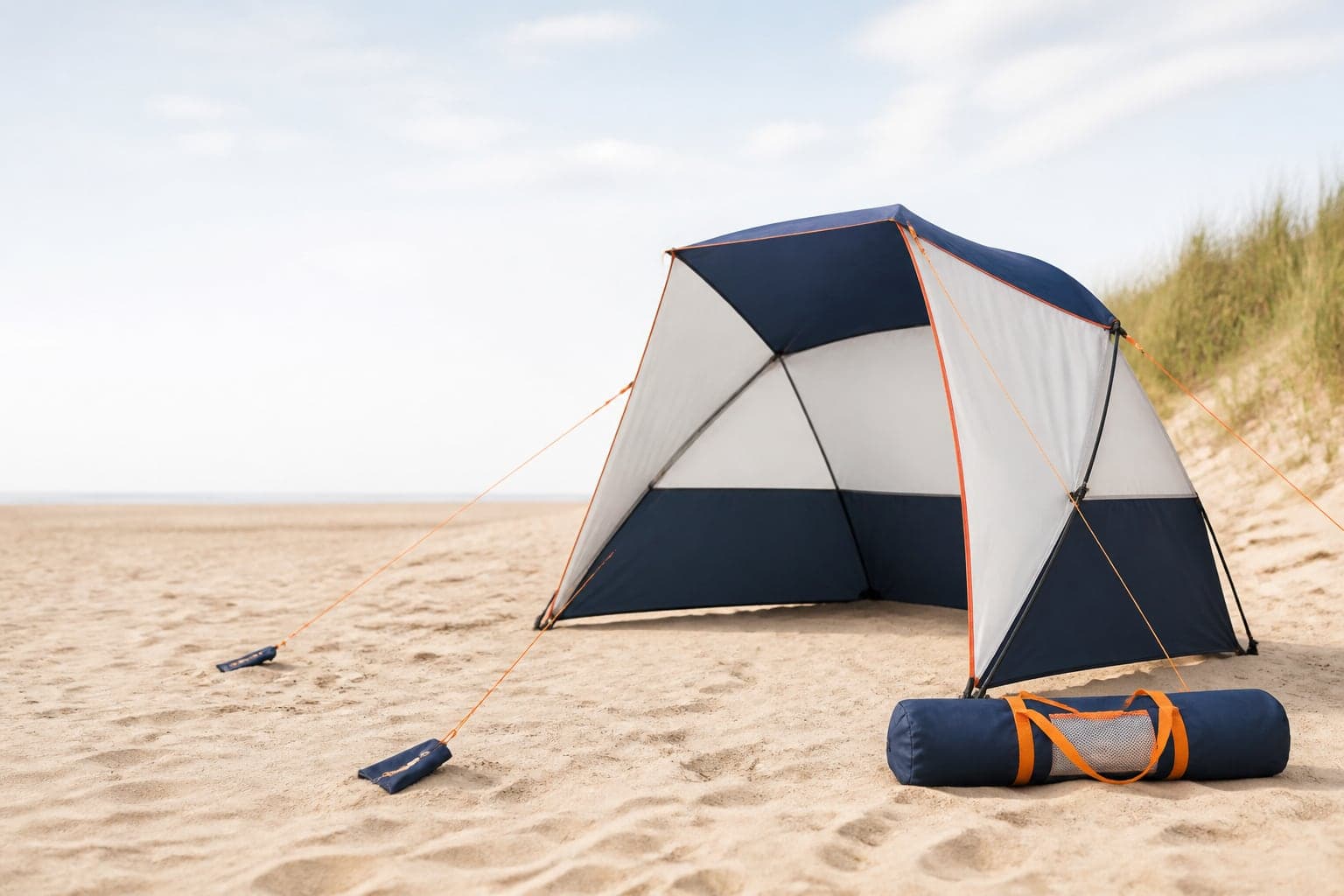 Compact beach sun shelter with fabric, frame and carry bag on a sandy beach